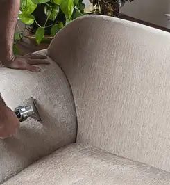 Professional upholstery cleaner deep-cleaning a fabric sofa with a handheld extraction tool and hose Scottsdale, AZ.